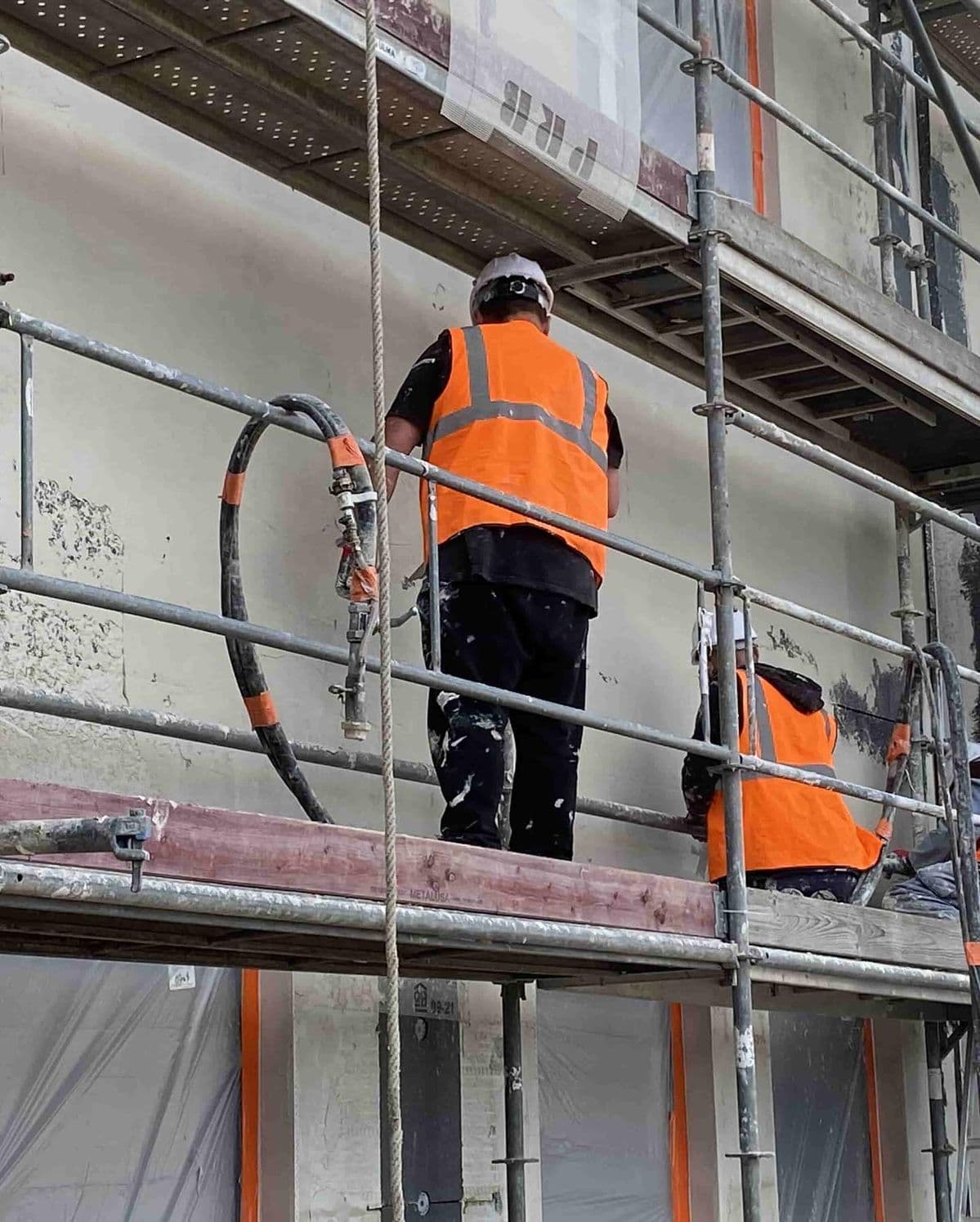 Omítkářská parta při strojním omítání na lešení