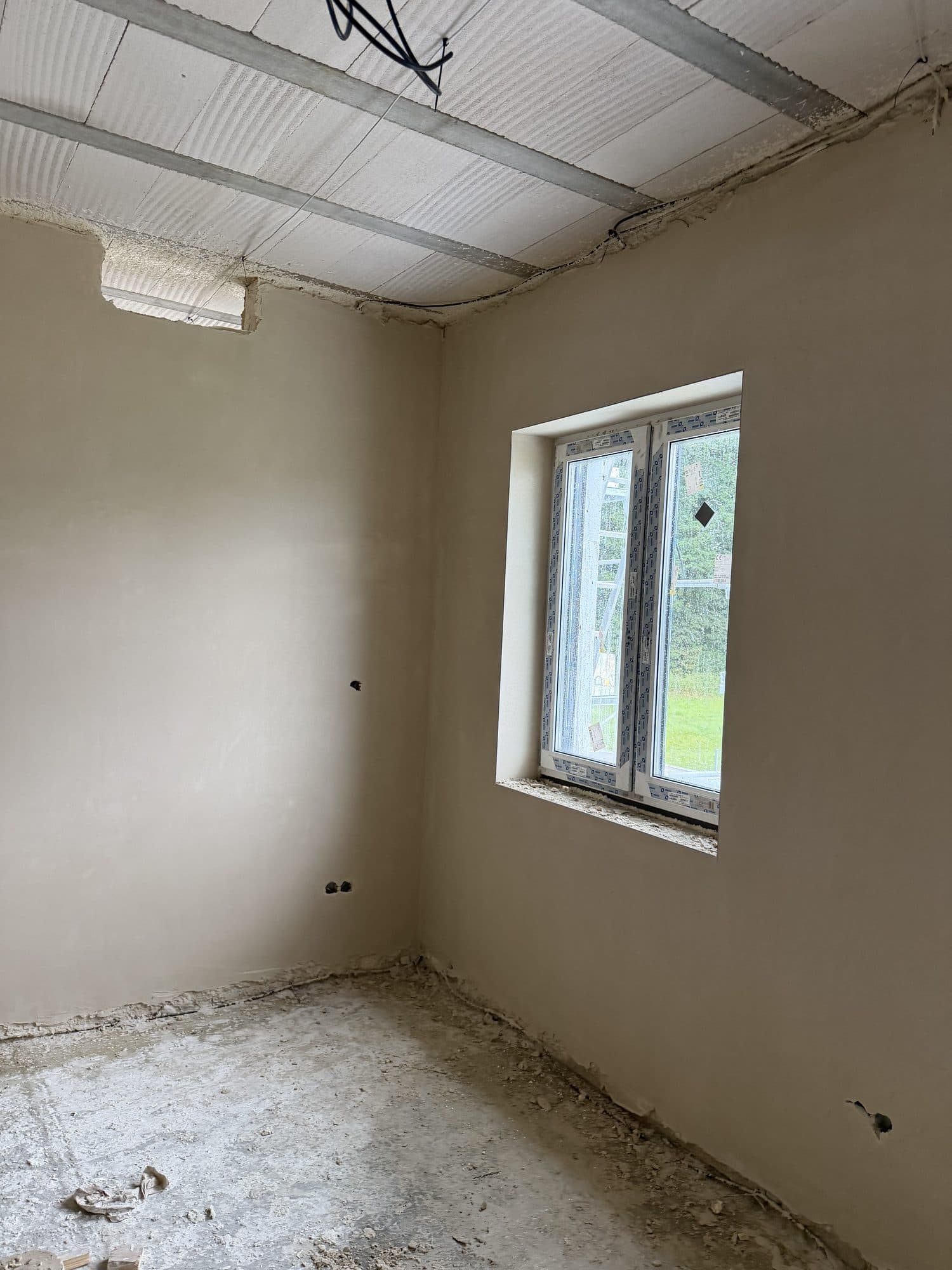 Dokončené omítky stěn i ostění v pokoji novostavby