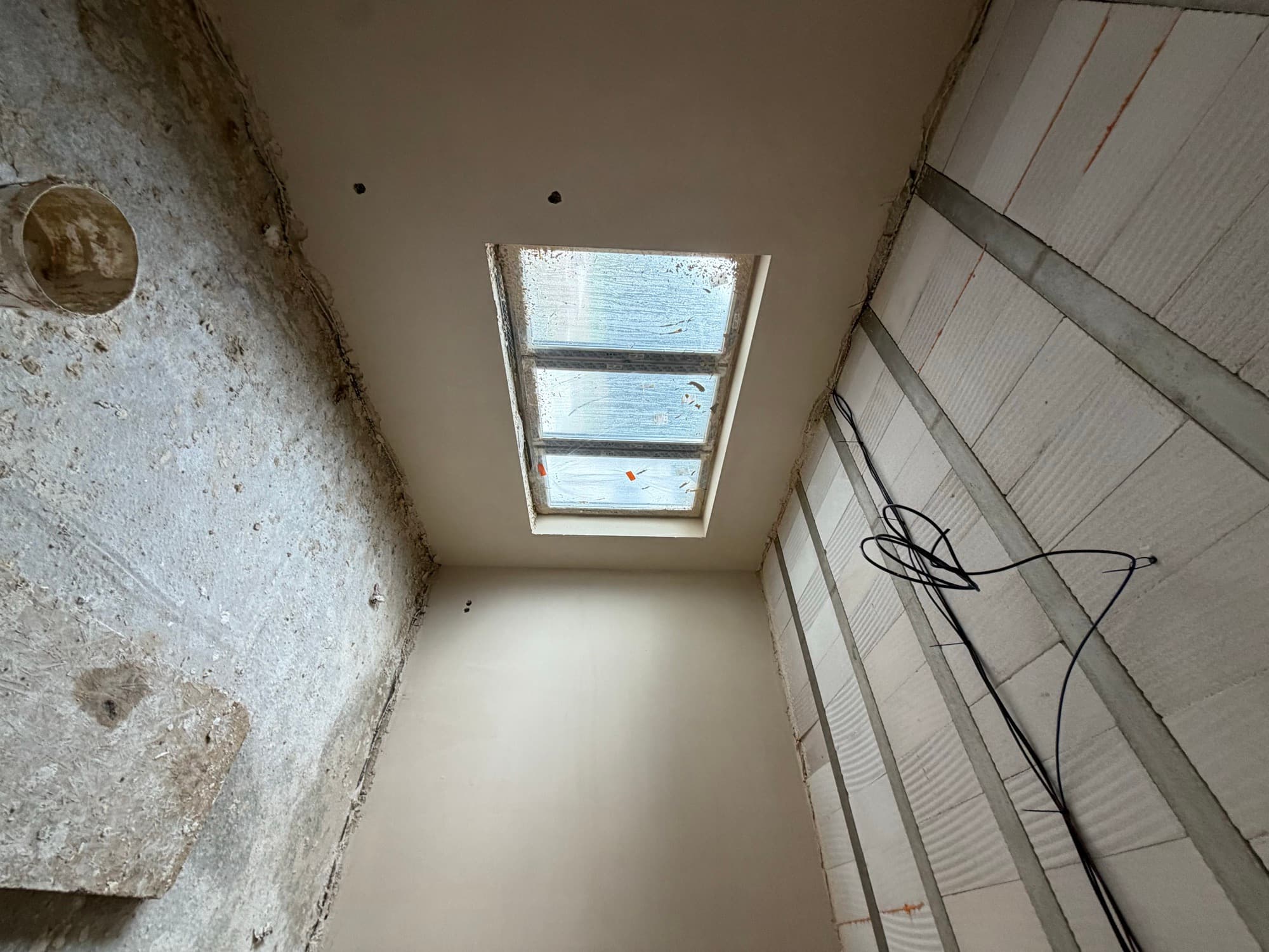 Omítnutý pokoj s elektrorozvody vedenými pod stropem